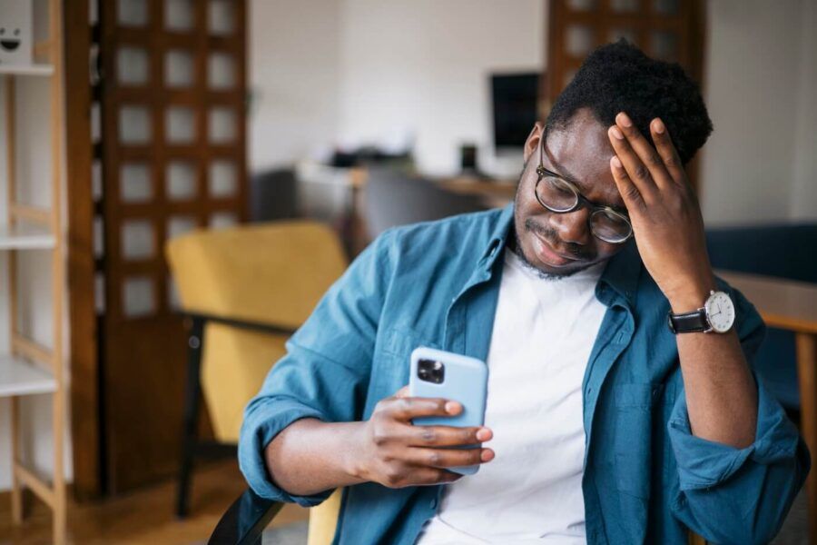 Concerned man wearing glasses looking at his smartphone