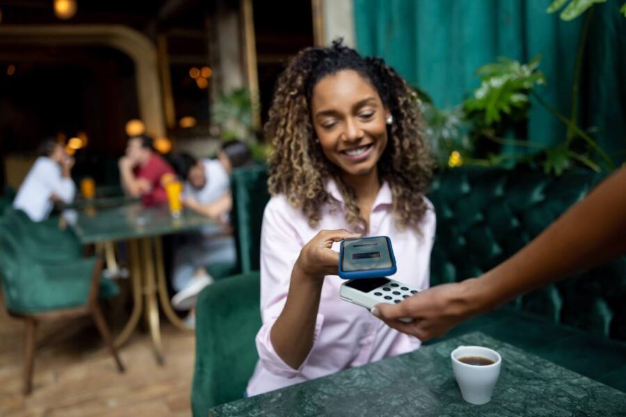 Smiling woman paying with her phone in the cafe