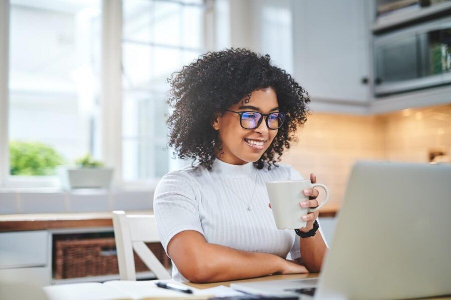 Smiling woman working on the laptop while drinking coffee