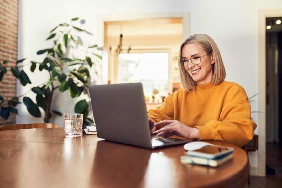Happy mature woman using laptop in the living room