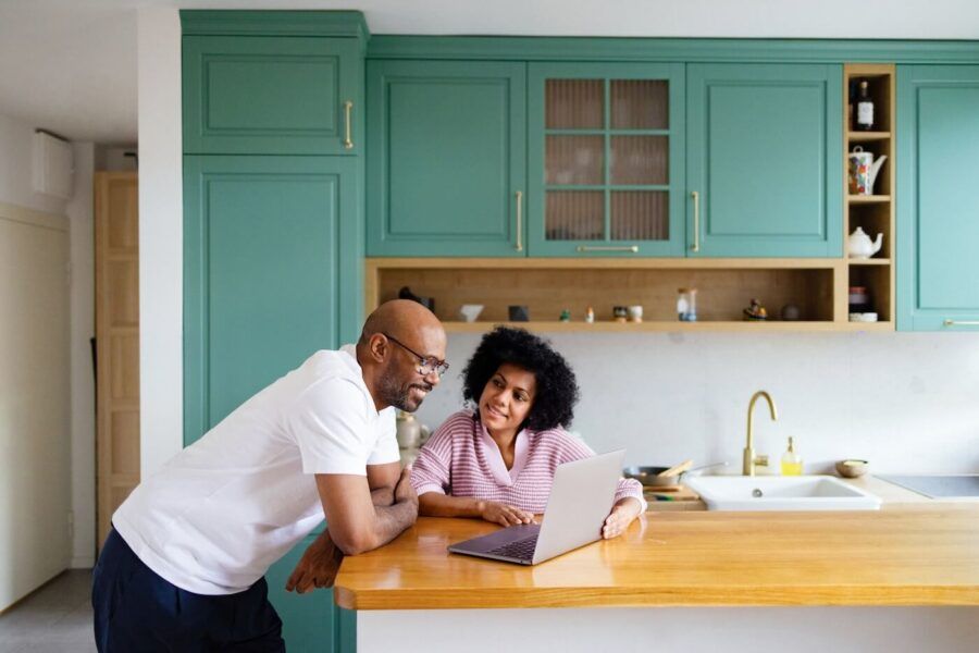 A couple using a laptop on a kitchen countertop