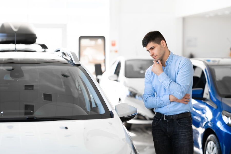 Concerned man looking at the vehicle in a dealership showroom.