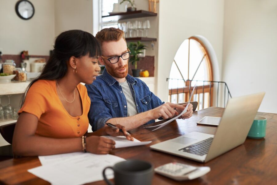 A couple looking at paperwork while sitting with a laptop.