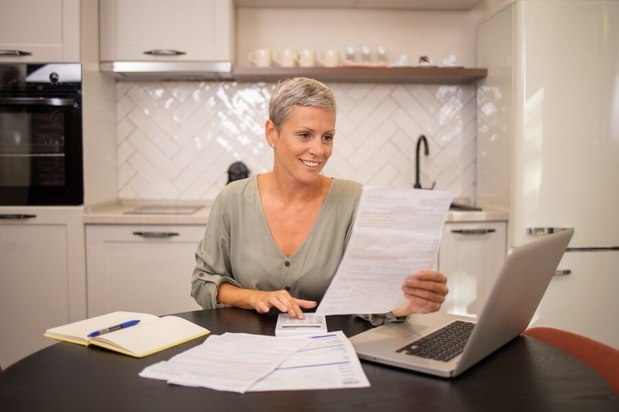 Woman reviewing credit paperwork at her kitchen table.