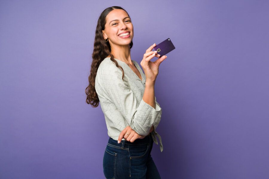 Happy young woman with good finances using her new debit card and smiling