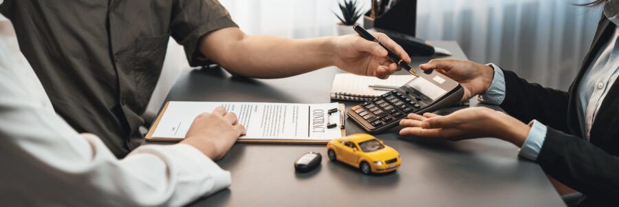 Car dealer preparing car loan with calculator.