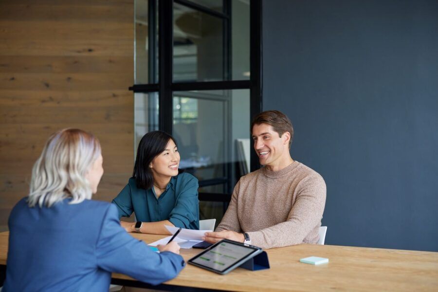 A man and a woman meeting with their investment advisor at a large table in an office.