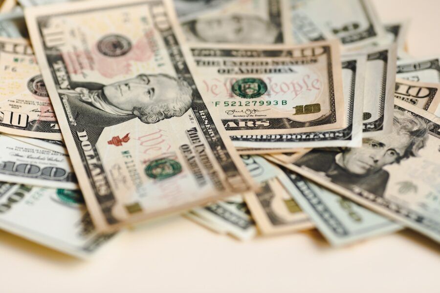 A close up shot of a pile of U.S. paper money on a white background.