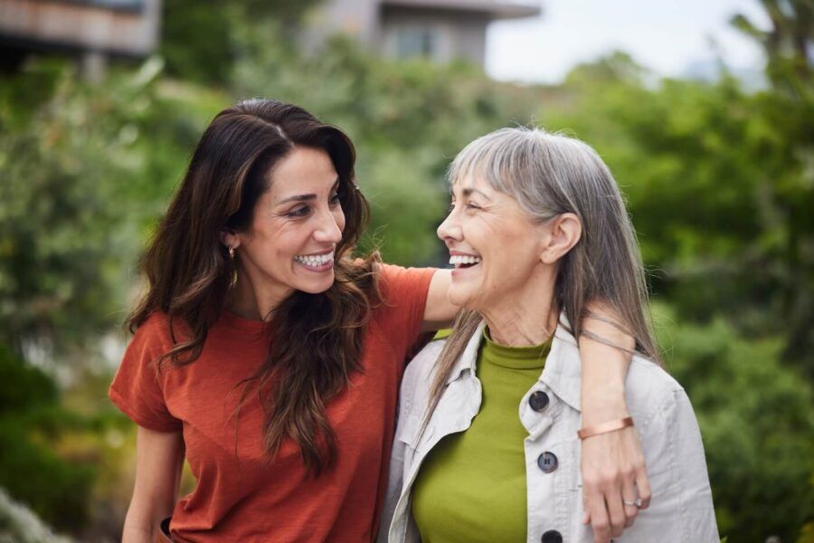 Smiling adult daughter hugging senior mother during a walk outdoors