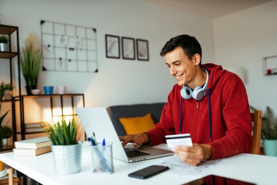 Smiling young man paying bills online in his home office