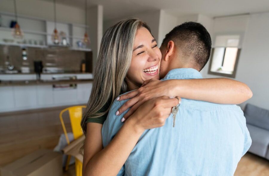 Happy young woman hugging a man while holding the keys from their new house