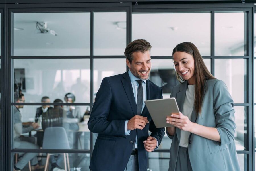 Smiling business woman showing something on the tablet to her colleague in the office