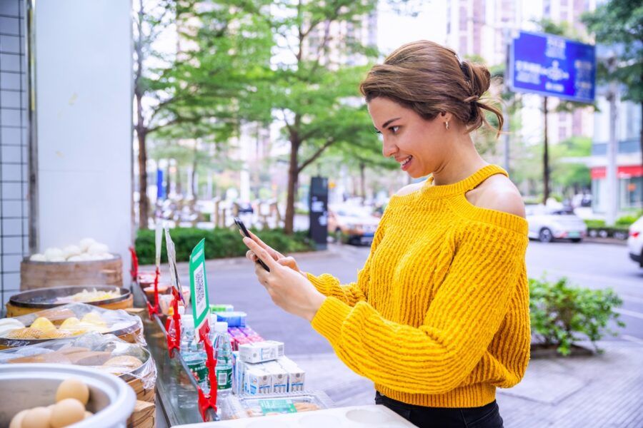 Woman holding smartphone, scanning QR code for contactless payment