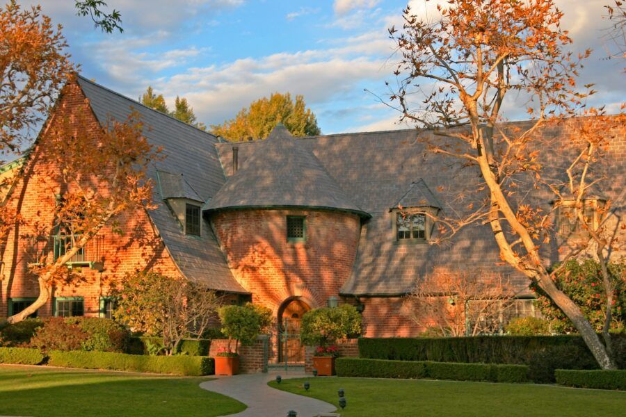 Brick tudor house looks like an autumn mansion amid trees losing their leaves in Beverly Hills, CA.