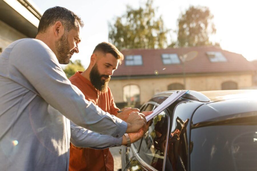 Two men inspecting the used car before buying
