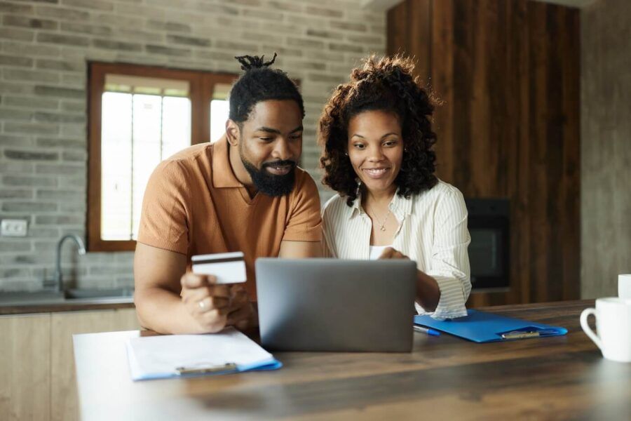 Happy couple using credit card online in their cozy kitchen