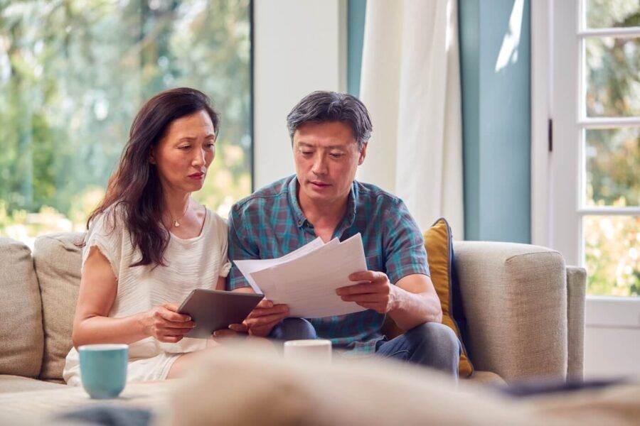 Focused mature couple reviewing their finances while using a tablet at home