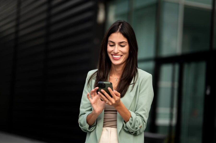 Smiling businesswoman checking her smartphone outdoors