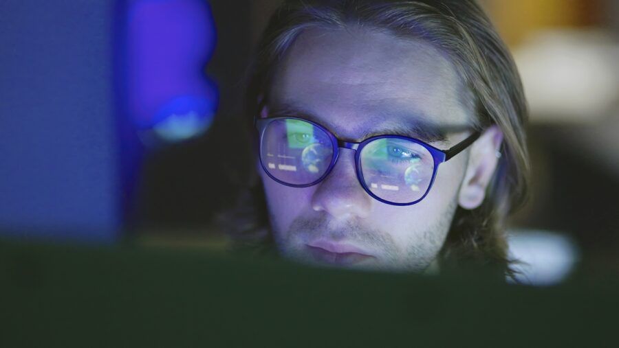 Close-up of a face of a young man, working at night in a dark office