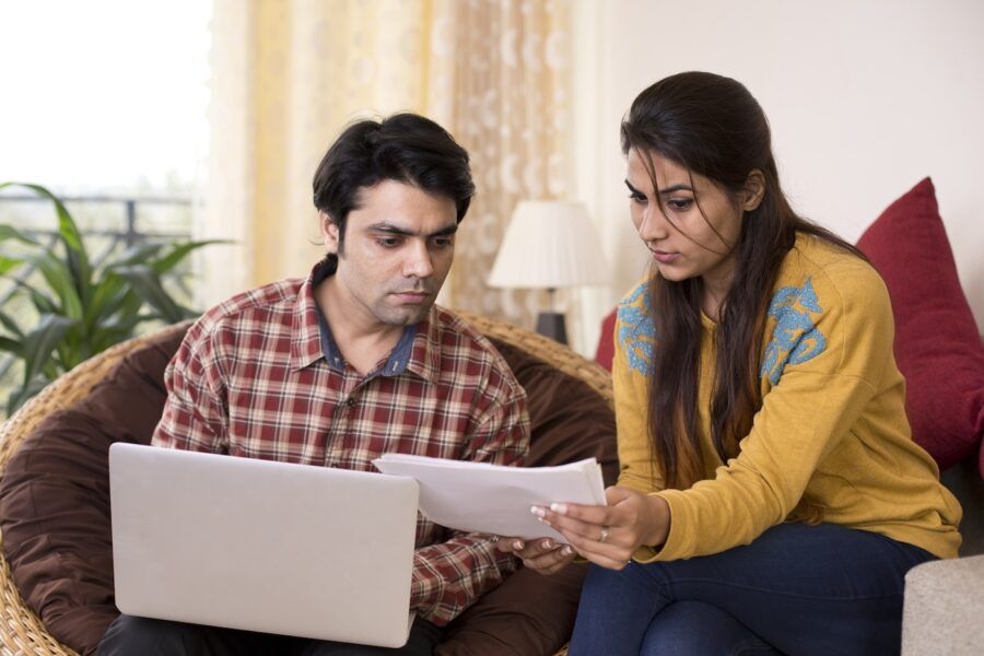 Young couple reading insurance documents at home.