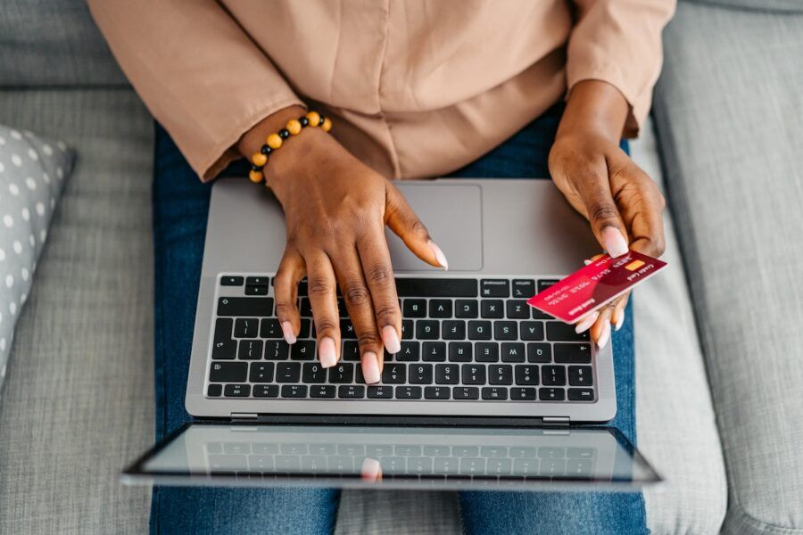 A woman with beautiful nails using her laptop to pay her credit card bill online at home.