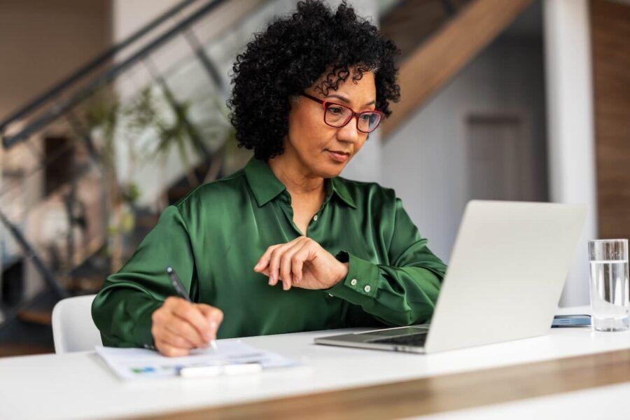 Focused businesswoman using her laptop in the office while making notes