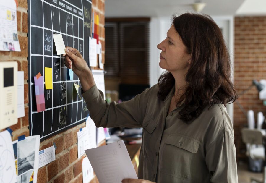 Woman pulling sticky note from a chalkboard calendar