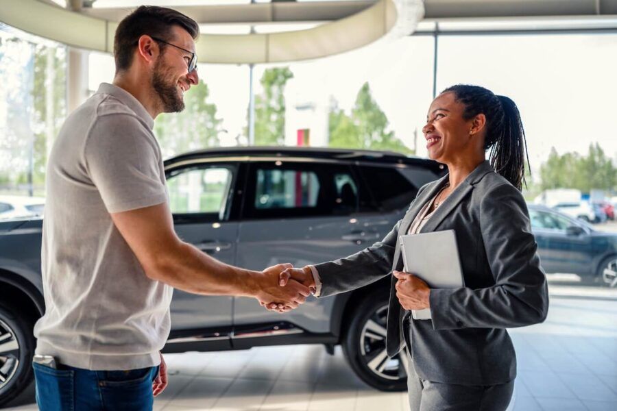 Male buyer of the car shaking hands with the seller in auto dealership
