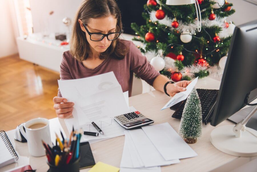 Woman sitting at the office desk and reading letter with christmas tree in the background