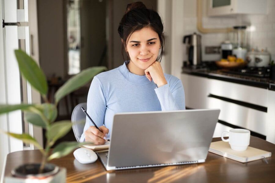 Young woman is using laptop and making notes