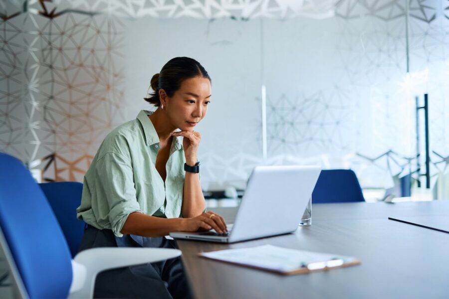 Focused young woman using her laptop in a modern conference room