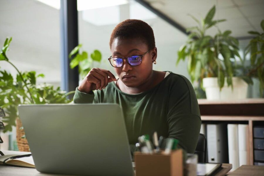 Focused woman in glasses is using her laptop