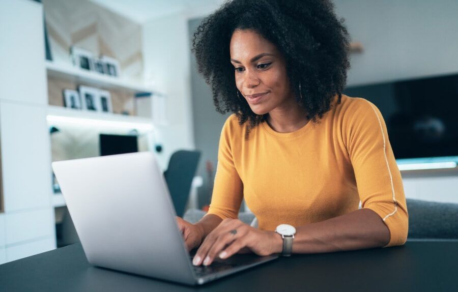 Focused young woman checking her credit score on a laptop at home