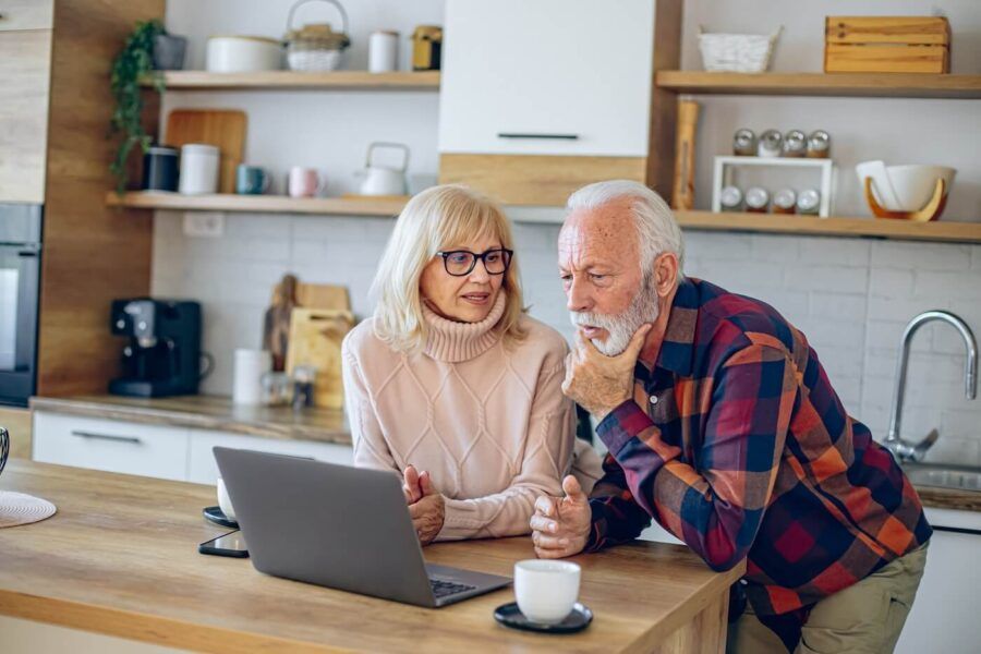 Focused senior couple using laptop in the kitchen