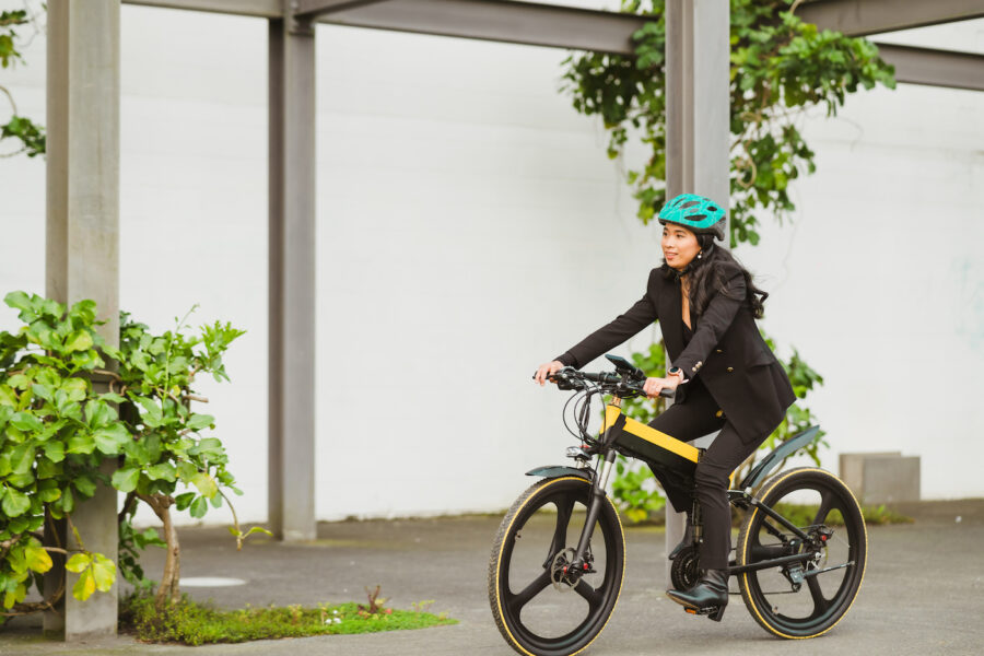 Portrait of a woman wearing protective helmet riding e-bike to work.