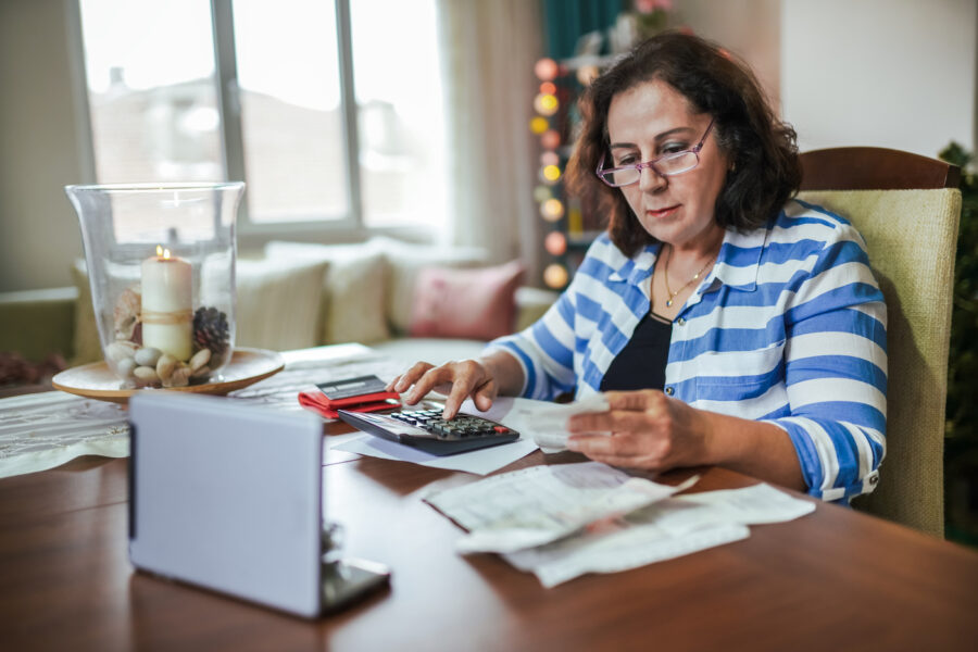 Woman sitting at kitchen table calculating taxes.