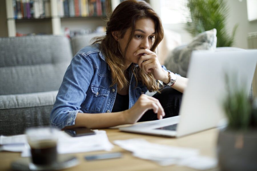 Worried young woman checking credit score on laptop at home