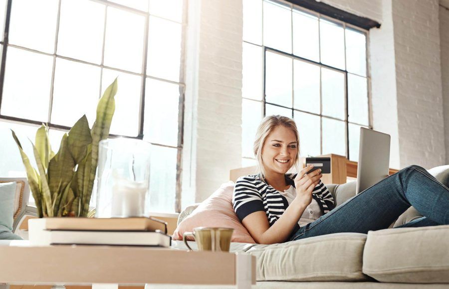 Woman sitting on the couch and online shopping with her credit card.