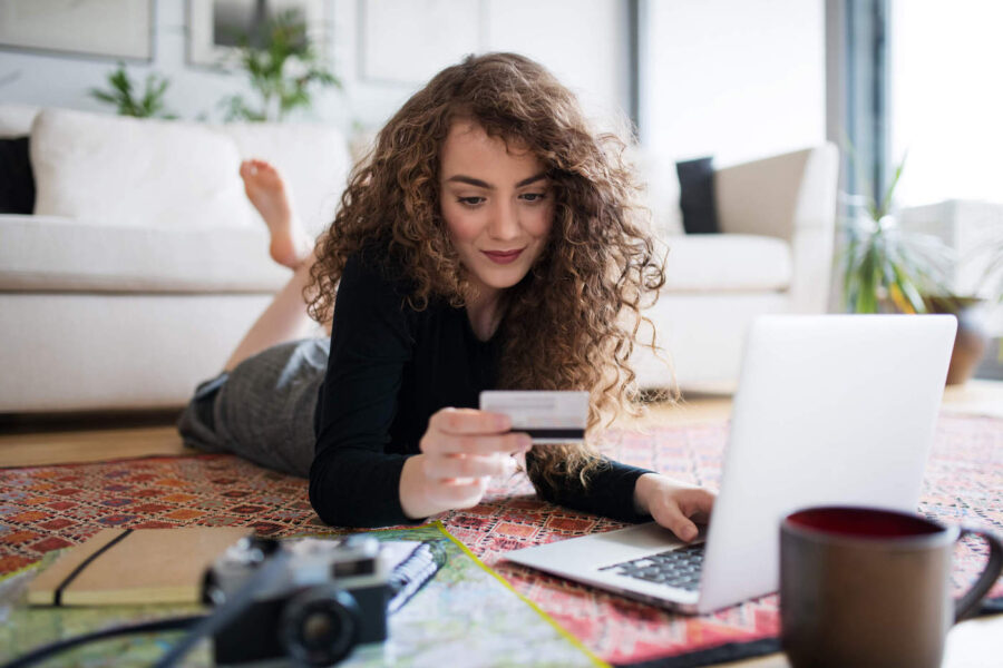 Woman holding credit card while looking up tips for spending wisely during the holidays.