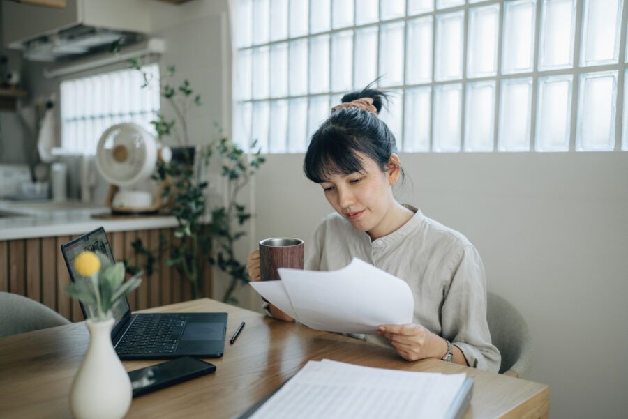 Woman sitting at her kitchen table looking at her loan papers.