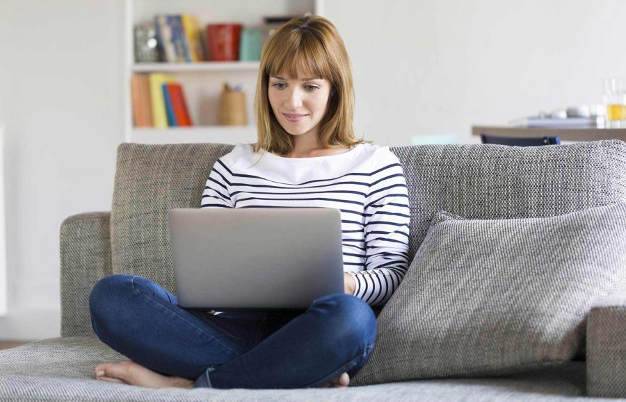 wanita dengan laptop duduk di sofa