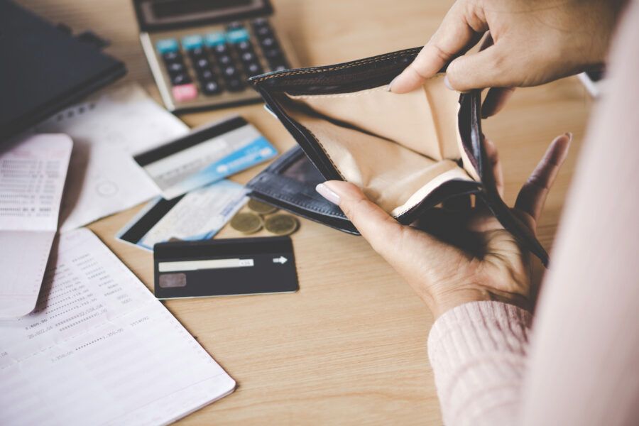 Woman opening empty wallet, low on cash