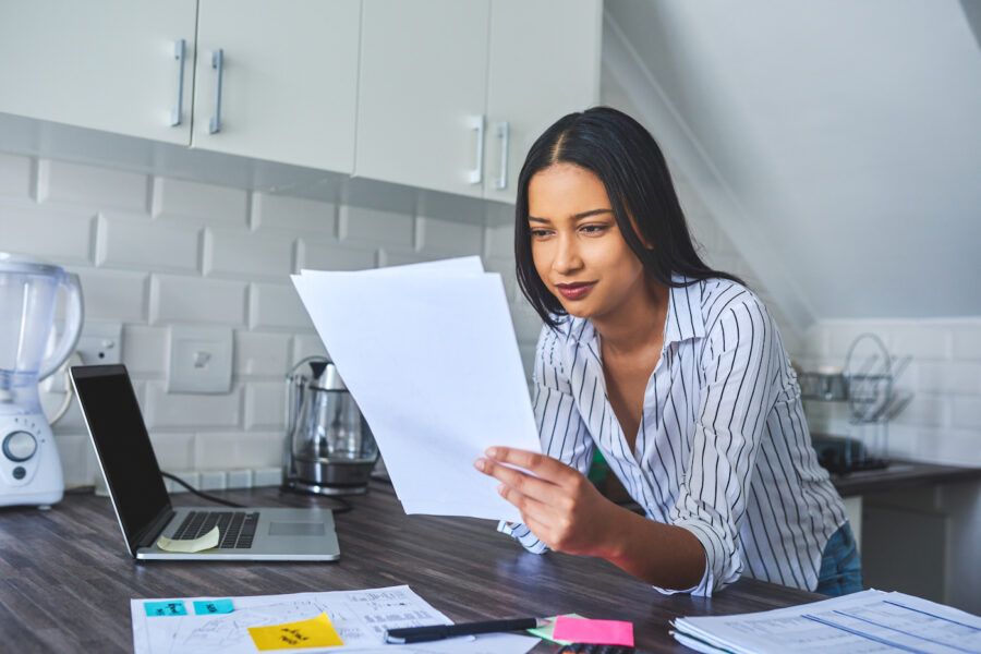 Cropped shot of a woman standing alone and going through investment paperwork in her home