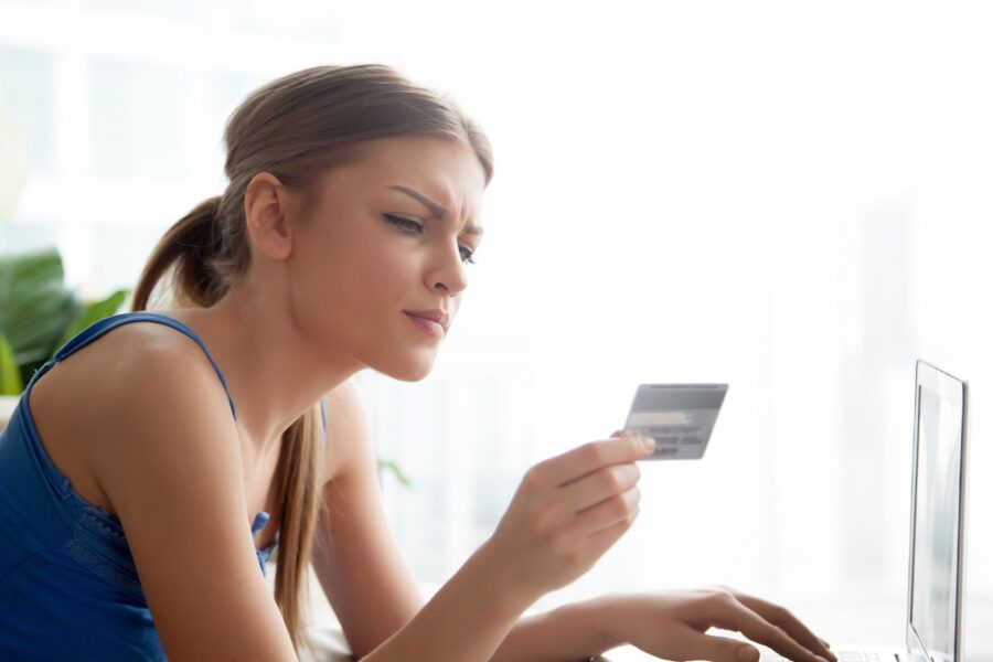 Womaan holding a credit card and looking at it scrutinously.