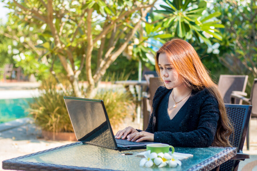 Woman sitting outside checking her savings account on her laptop