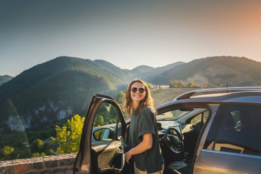 Young woman traveling by car in the mountains, parked by a scenic overlook