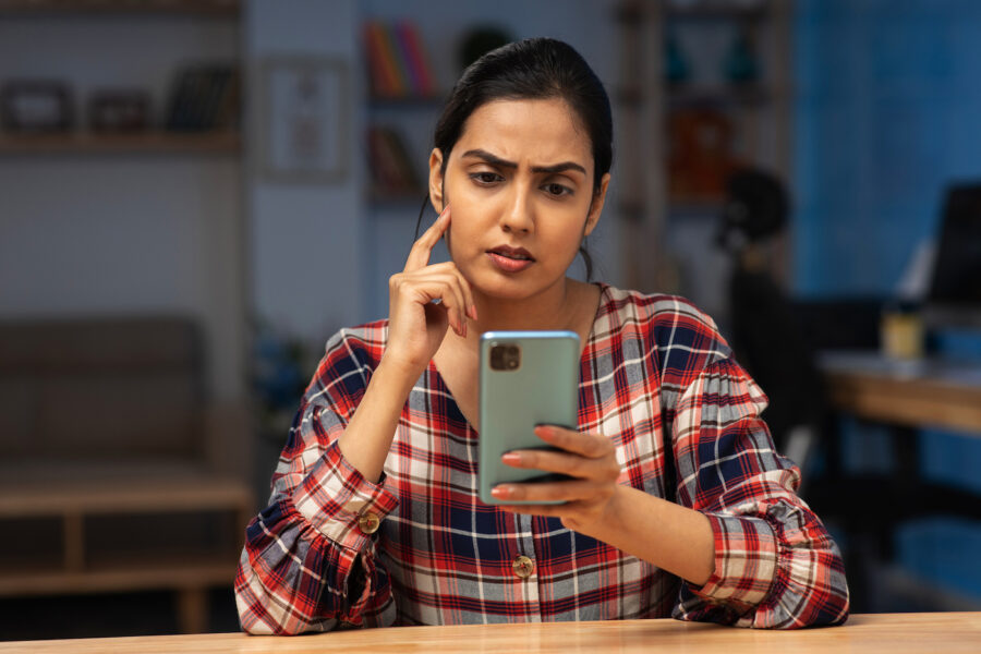 Portrait of woman staring at phone with concern