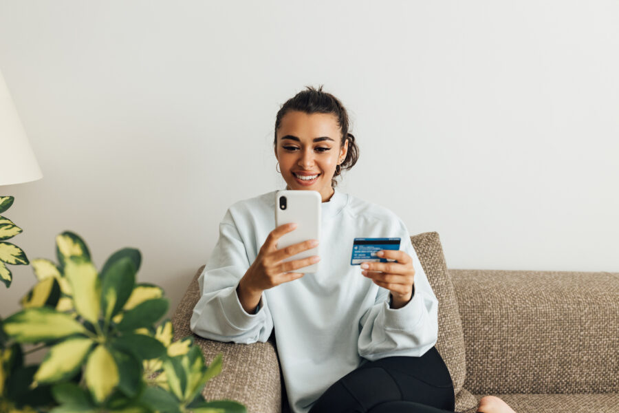 Smiling woman using smartphone and card.