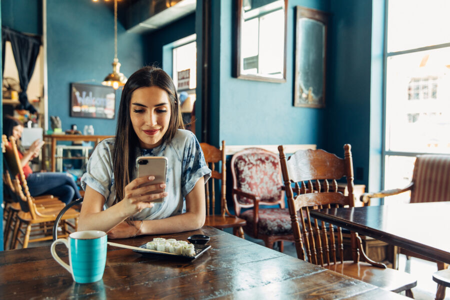 Woman using phone in cafe to check her credit limit