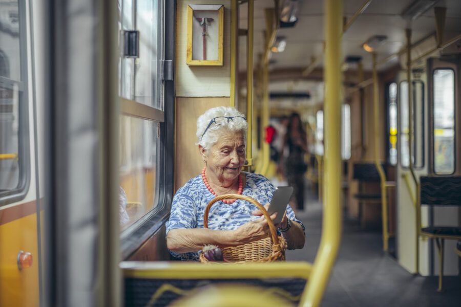 Senior woman using a mobile banking app on her phone while taking the bus